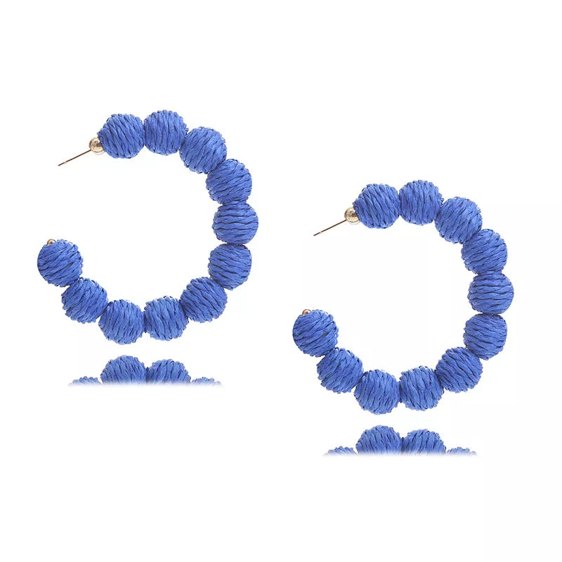 Blue raffia grass C-hoop earrings with textured ball details.