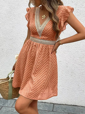 Chevron textured V-neck mini dress in burnt coral with lace trim and defined waist.