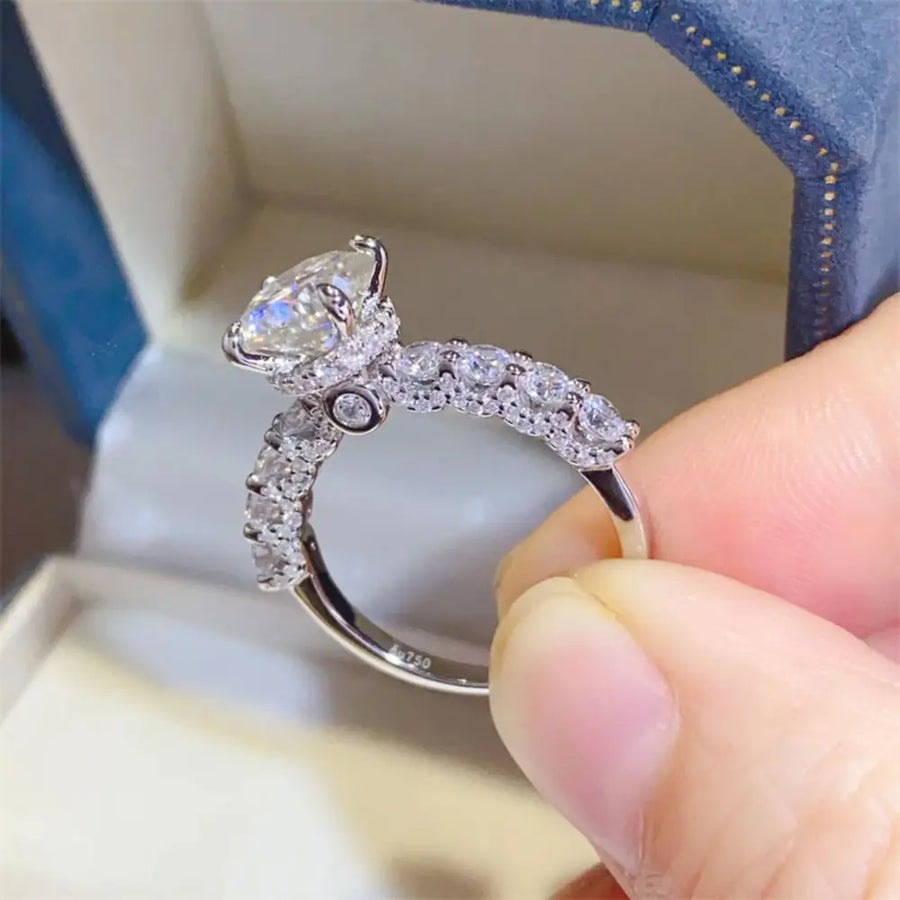 Silver moissanite halo ring with pavé band and marquise center stone.