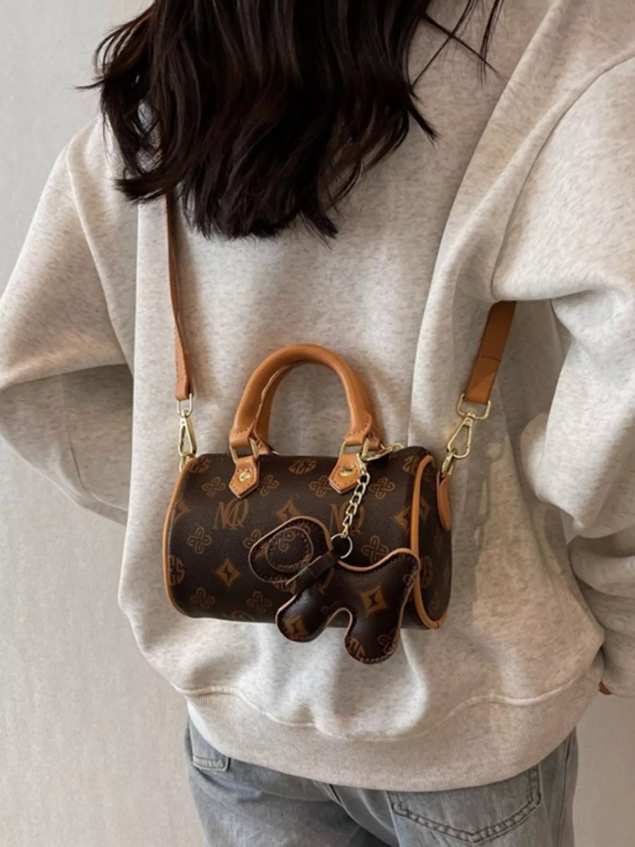 Brown mini barrel crossbody bag with elephant charm and monogram print