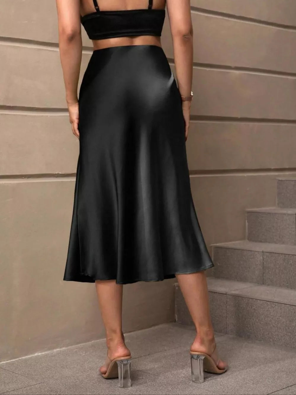 Black satin high-waisted midi skirt with a flowing A-line cut.