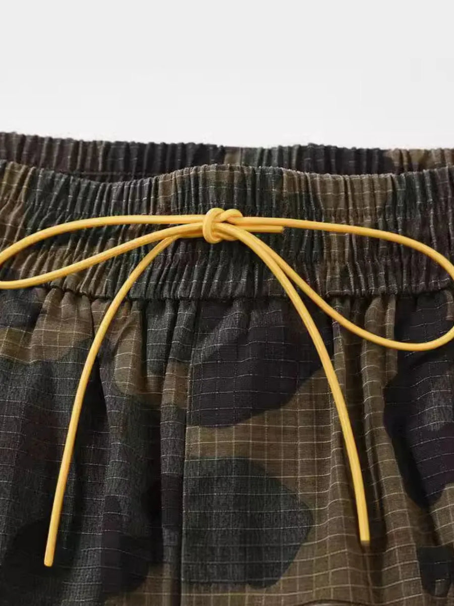Utility camo cargo shorts with elastic waistband and yellow drawstring detail.