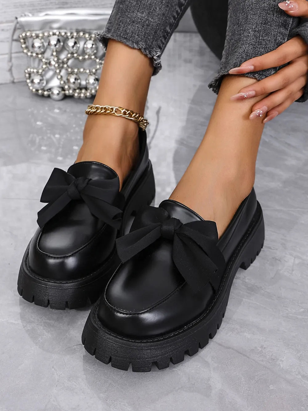 Black matte platform bow loafers with chunky soles.