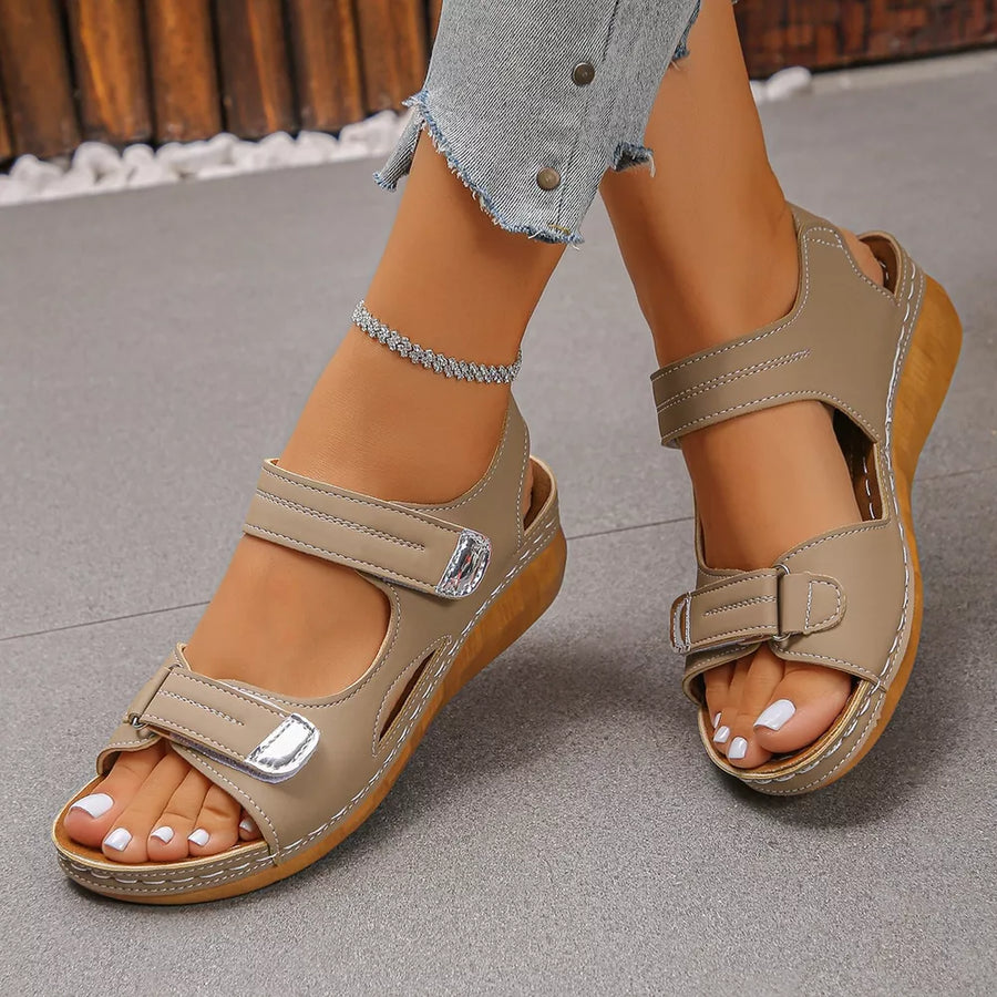 Apricot adjustable wedge sandals with hook-and-loop straps and a wooden sole detail.