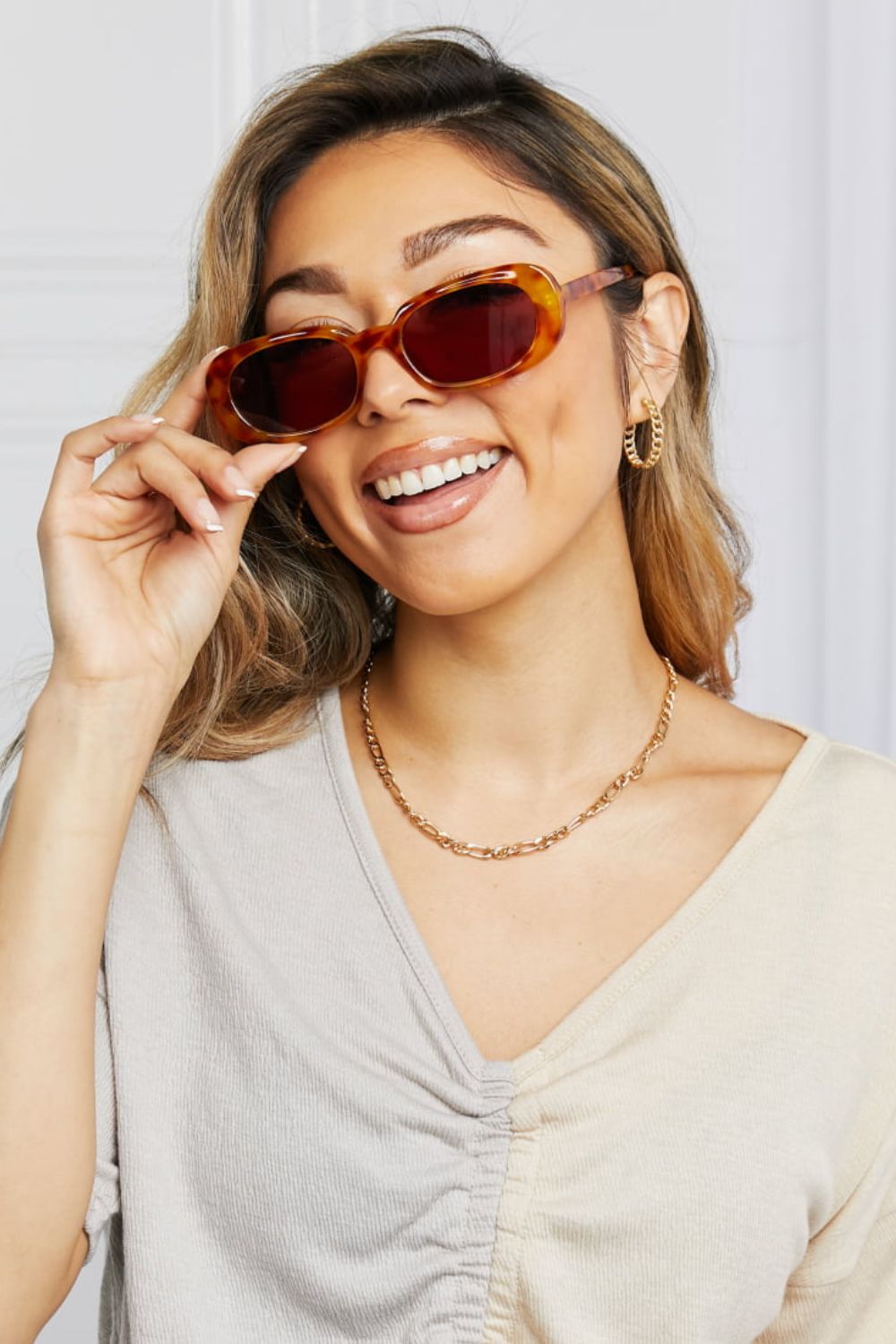Tortoiseshell oval sunglasses with sunset lenses and a woman smiling.