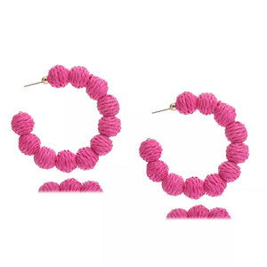 Raffia grass C-hoop earrings in pink, featuring textured spherical beads and gold-tone posts.