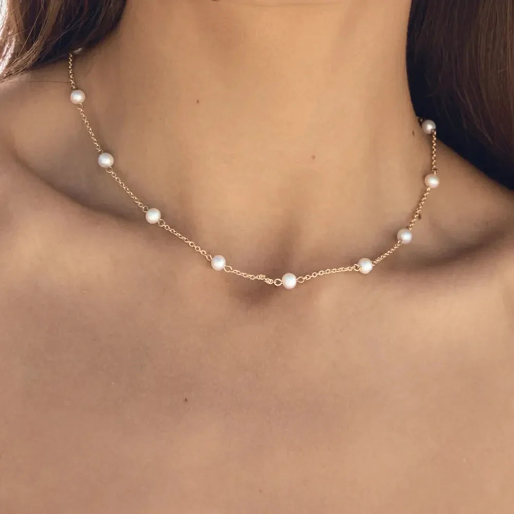 Delicate gold chain necklace with scattered pearls.