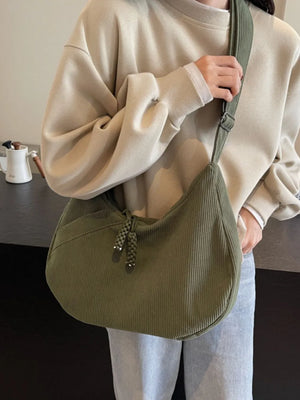 Moss green corduroy crescent shoulder bag with braided tassels and adjustable strap.