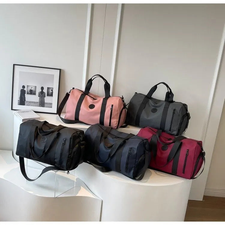 Duffel bags in black, dark navy, dusty pink, dark gray, and burgundy with contrast straps and zippered pockets.