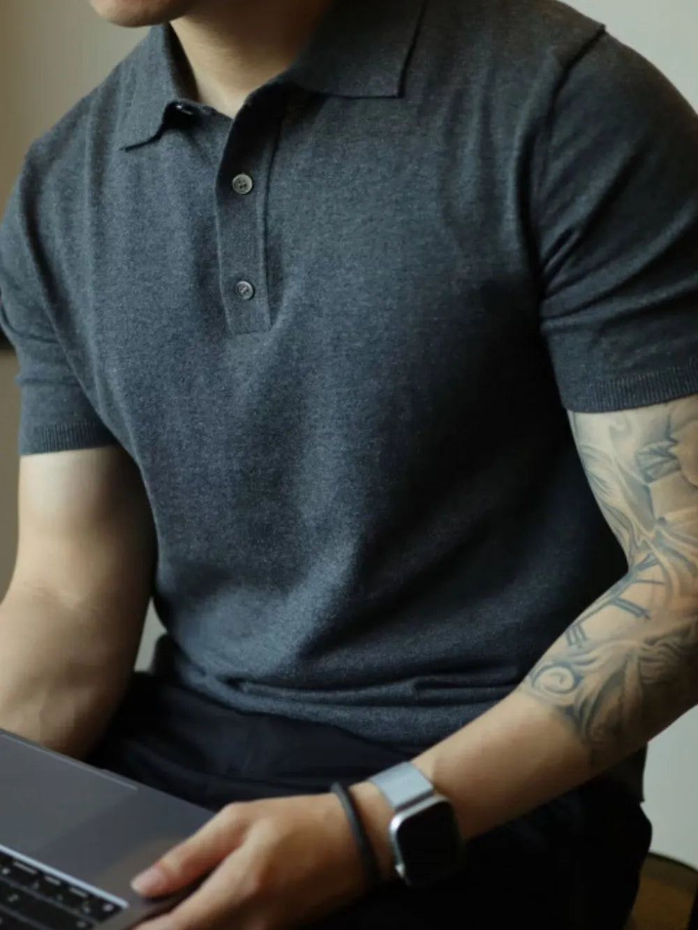 Dark gray fine-gauge knit polo shirt with a refined placket and button detail.