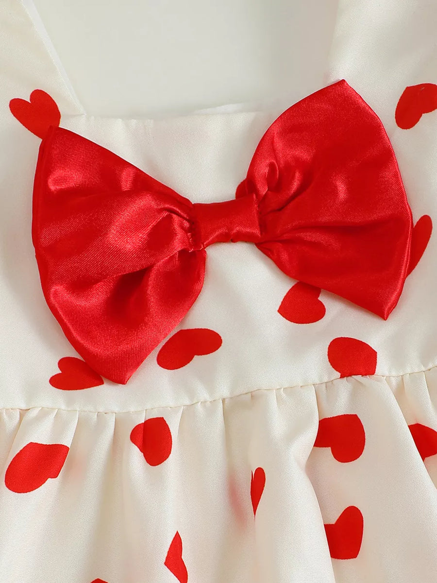 Baby dress with red heart print and satin bow detail.