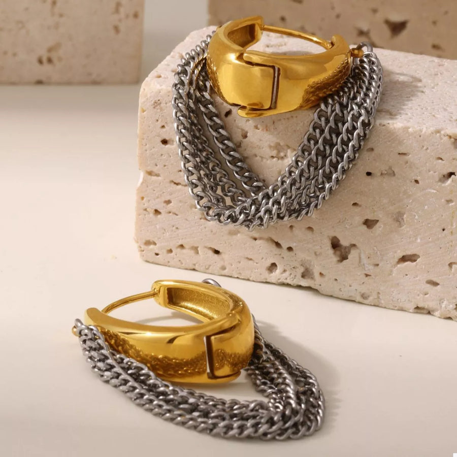 Chunky gold hoop earrings with layered silver chains.