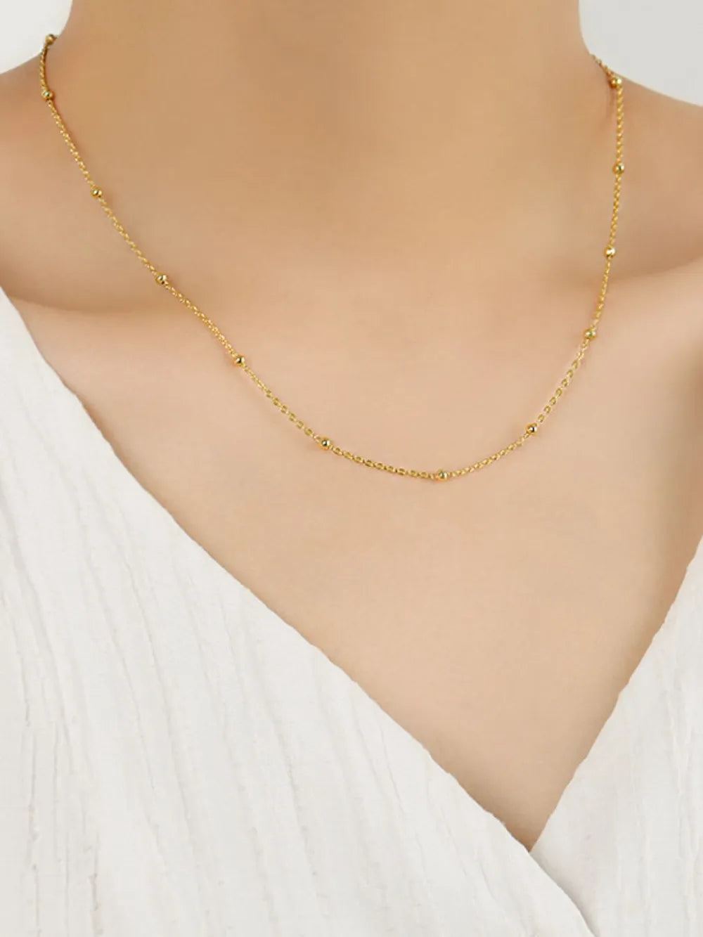 Gold delicate orb chain necklace with small beads on a fine chain.
