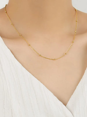 Gold delicate orb chain necklace with small beads on a fine chain.