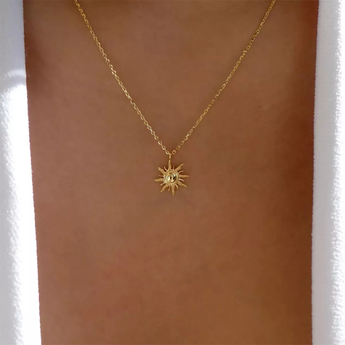 Gold sunburst pendant necklace with lace trim detail on a delicate chain.