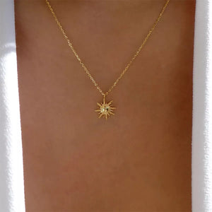 Gold sunburst pendant necklace with lace trim detail on a delicate chain.