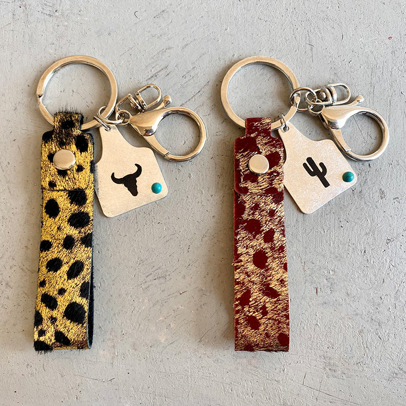 Cheetah print leather key fobs in white and burgundy with metal charms and turquoise accents.