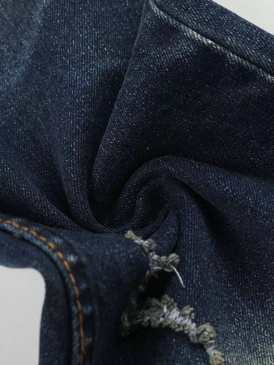 Distressed dark wash flare jeans in blue cotton with frayed hem detail.
