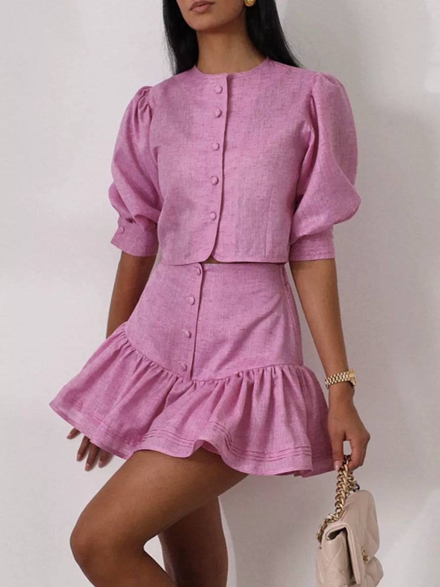 Pink linen blend crop top with puff sleeves and matching ruffled mini skirt.