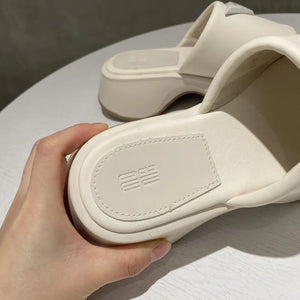 Ivory geometric platform slides with embossed branding detail on the sole.