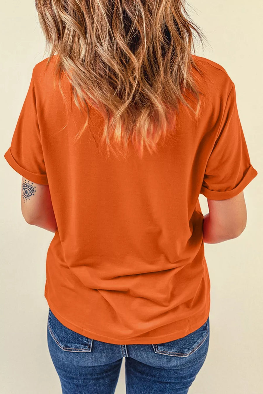 Orange t-shirt with rolled short sleeves and a crew neck, styled with blue jeans.