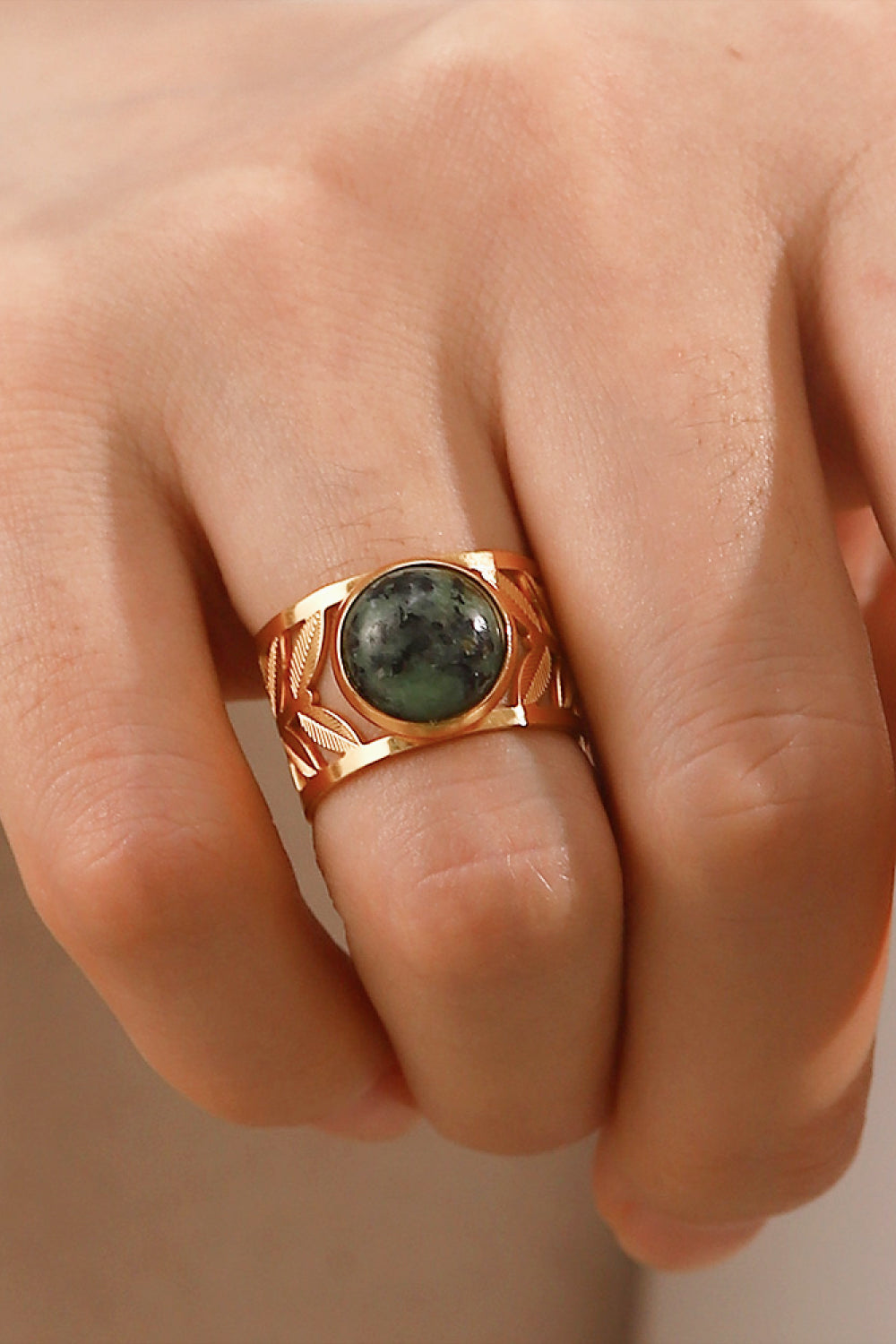 Leaf-cut gold ring with oval malachite stone and openwork leaf design.
