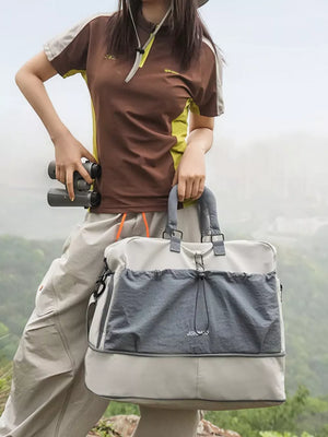 Crinkled nylon travel bag in gray and beige with drawstring front pocket.