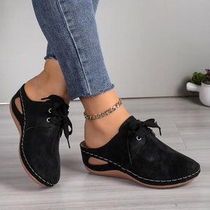 Black perforated lace-up mule flats with white stitching and cut-out sides.