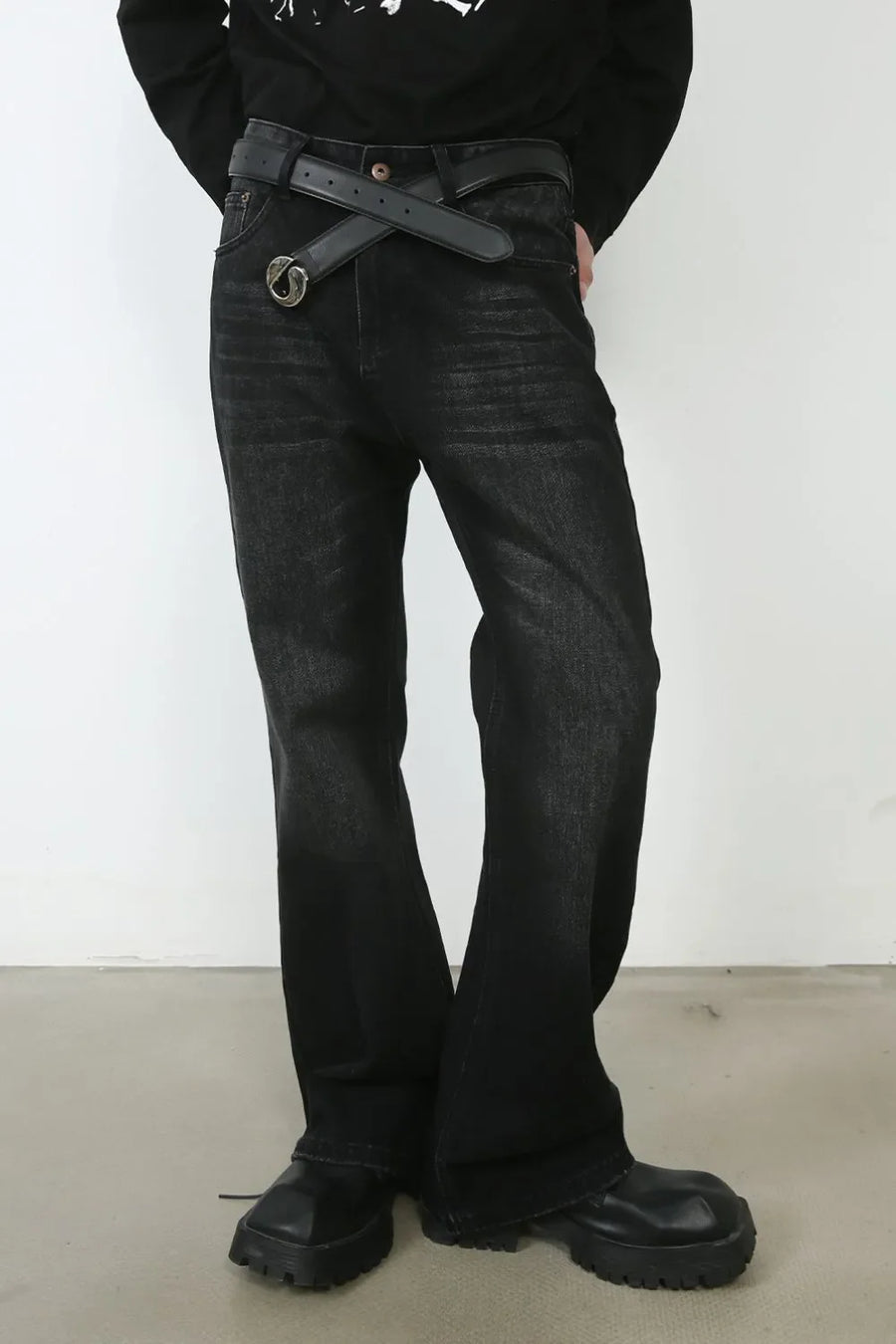 Faded black denim flare jeans with a distressed wash and a black belt.
