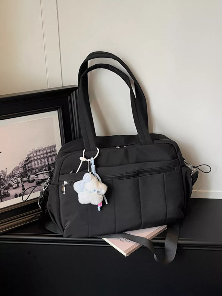 Black quilted nylon tote bag with star charm and multiple zippered pockets