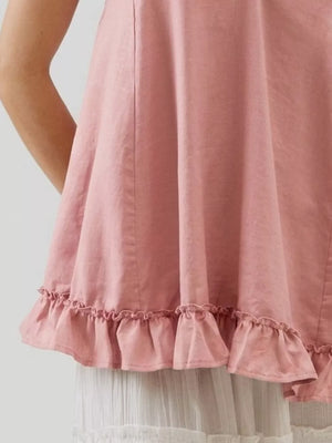 Pink camisole with adjustable tie straps and ruffled hem detail.