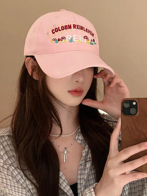 Blush pink baseball cap with playful mushroom embroidery and text detail.