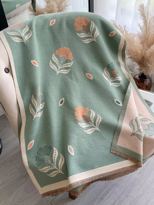 Green floral print fringed shawl with beige trim and tassels.