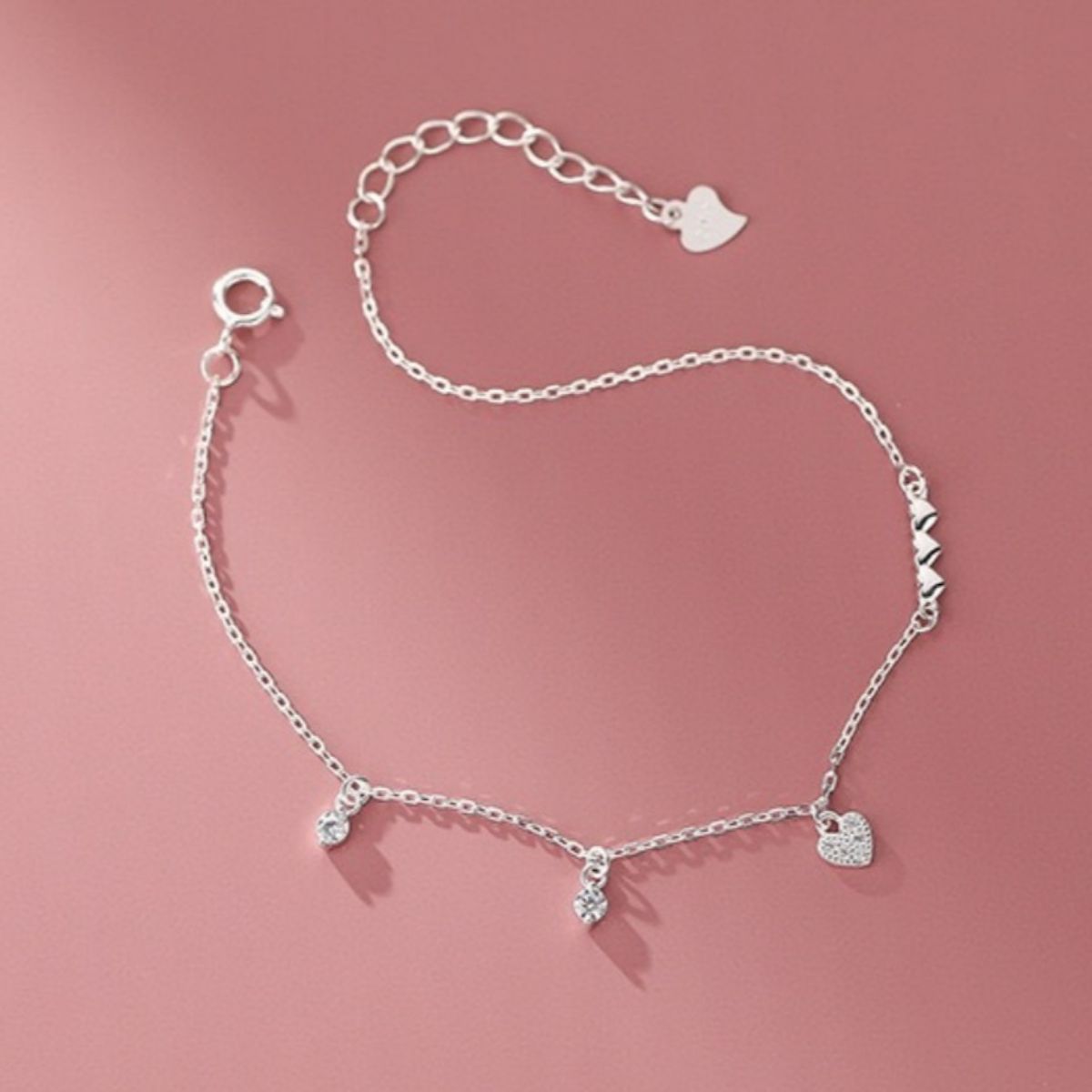 Silver charm bracelet with pavé heart and cubic zirconia accents.