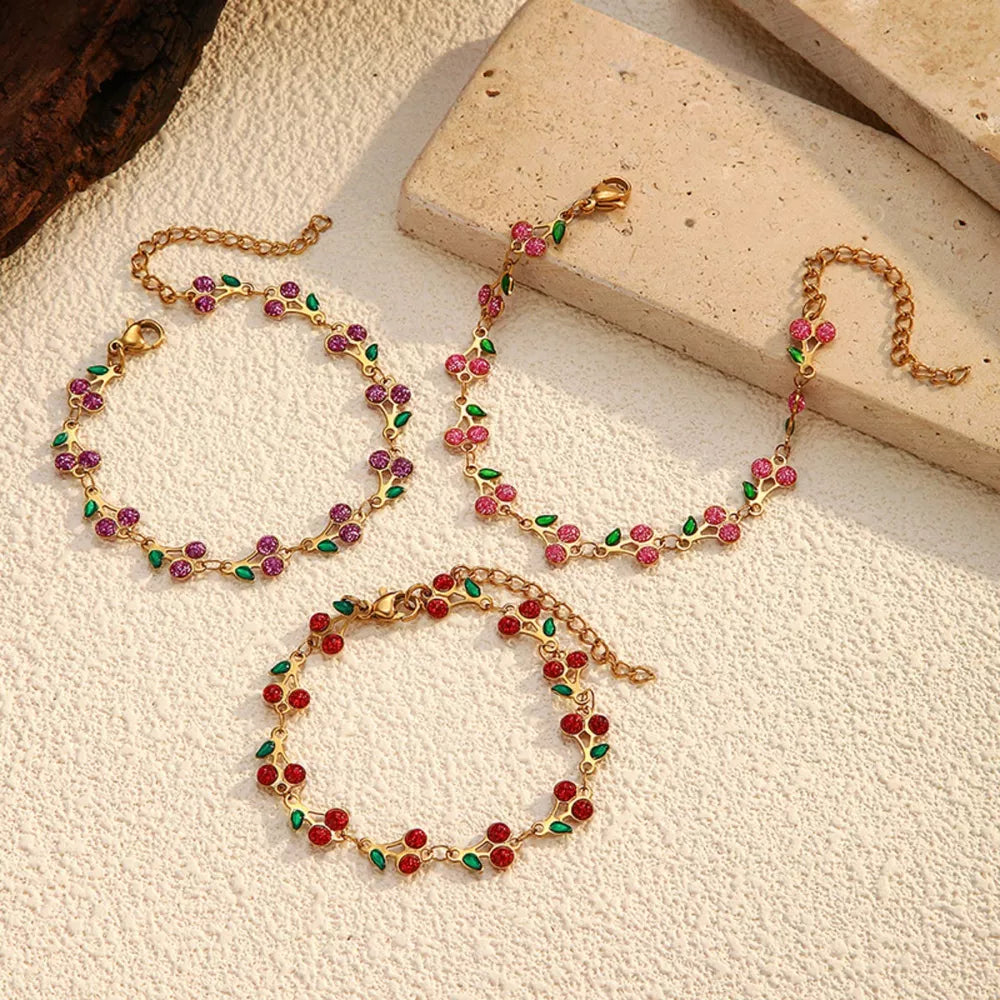Gold-plated cherry cluster bracelets in red, pink, and purple with green leaves.