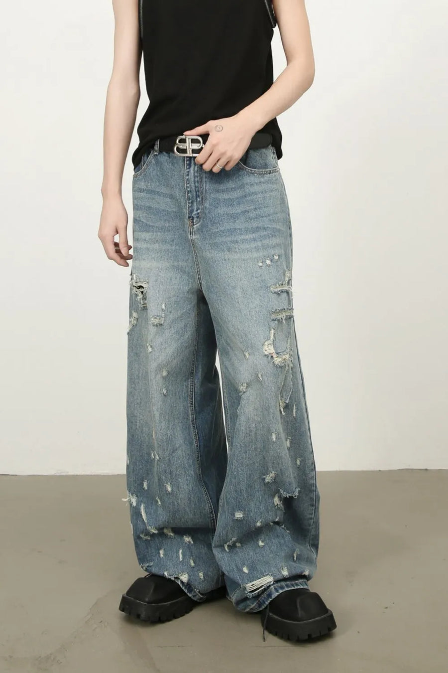 Distressed palazzo jeans in medium wash denim with raw edge detail and ripped accents.