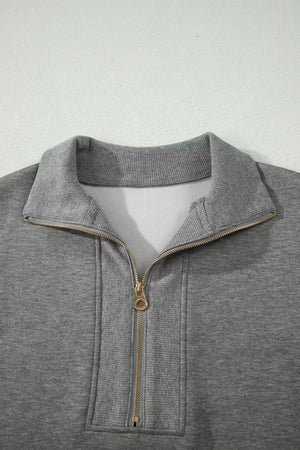 Chic dark gray half-zip polo sweatshirt with gold zipper detail and ribbed collar.