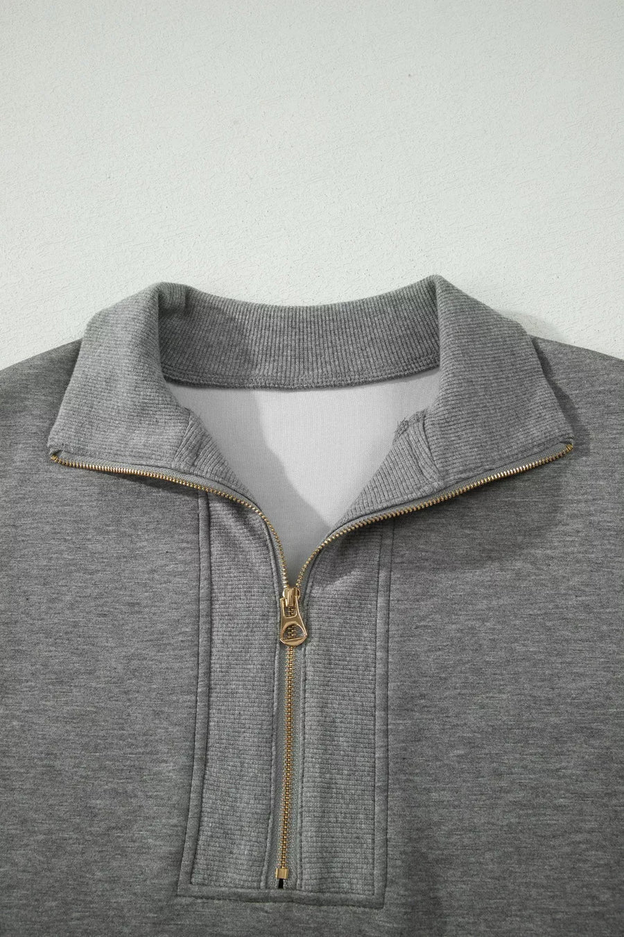 Chic dark gray half-zip polo sweatshirt with gold zipper detail and ribbed collar.