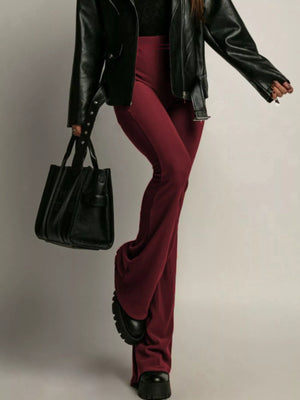 High-waisted flared trousers in red, styled with a black jacket and platform shoes.