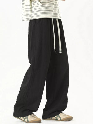 Black track pants with white drawstring detail and a relaxed fit.