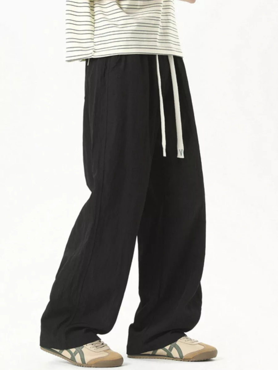 Black track pants with white drawstring detail and a relaxed fit.