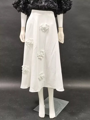 White midi skirt with floral applique detail.