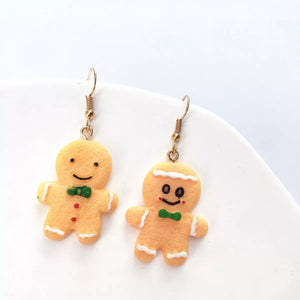 Gingerbread man holiday earrings with green bow ties and white icing details.
