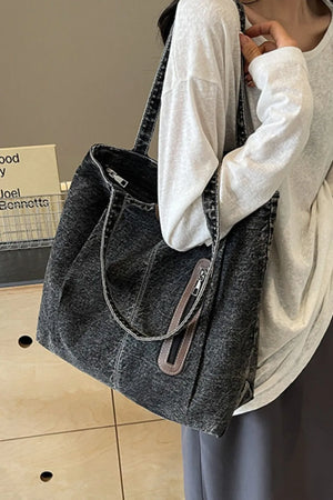 Denim shopper bag in dark wash with leather trim and zipper pocket detail.