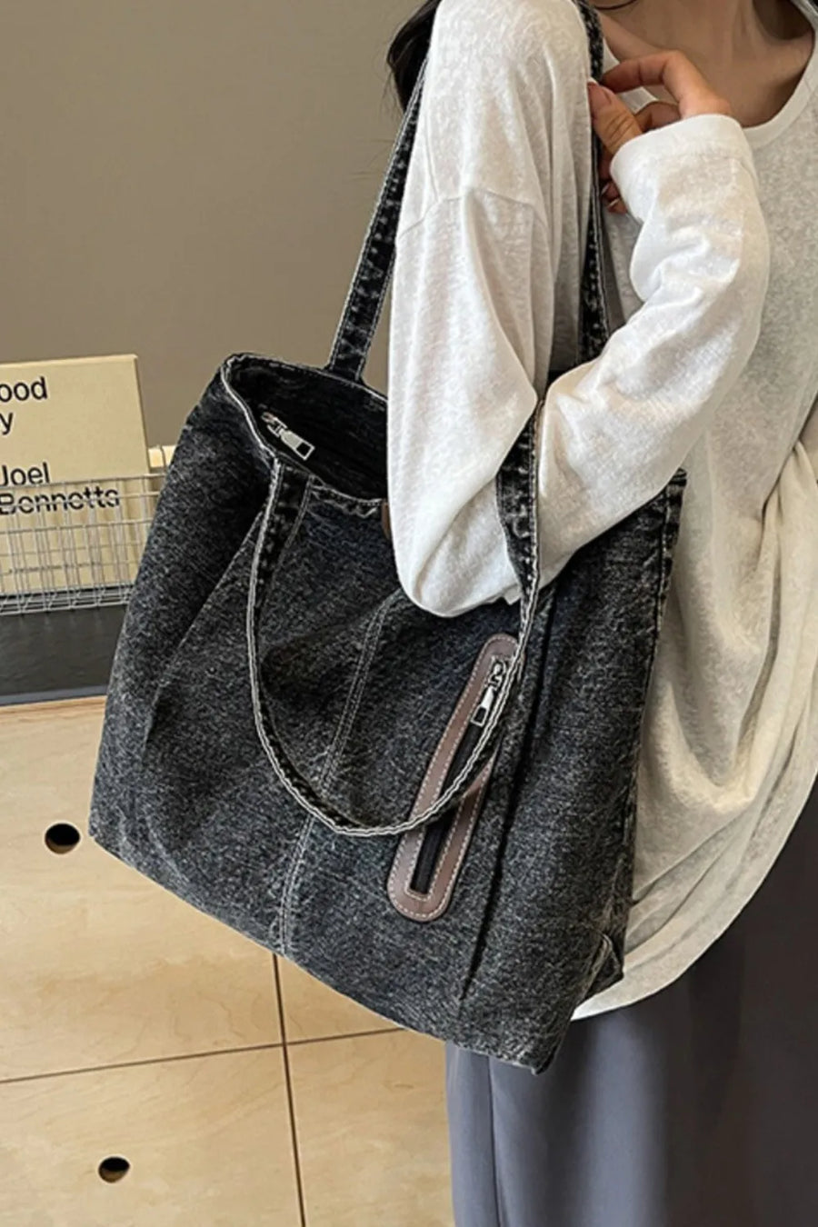 Denim shopper bag in dark wash with leather trim and zipper pocket detail.
