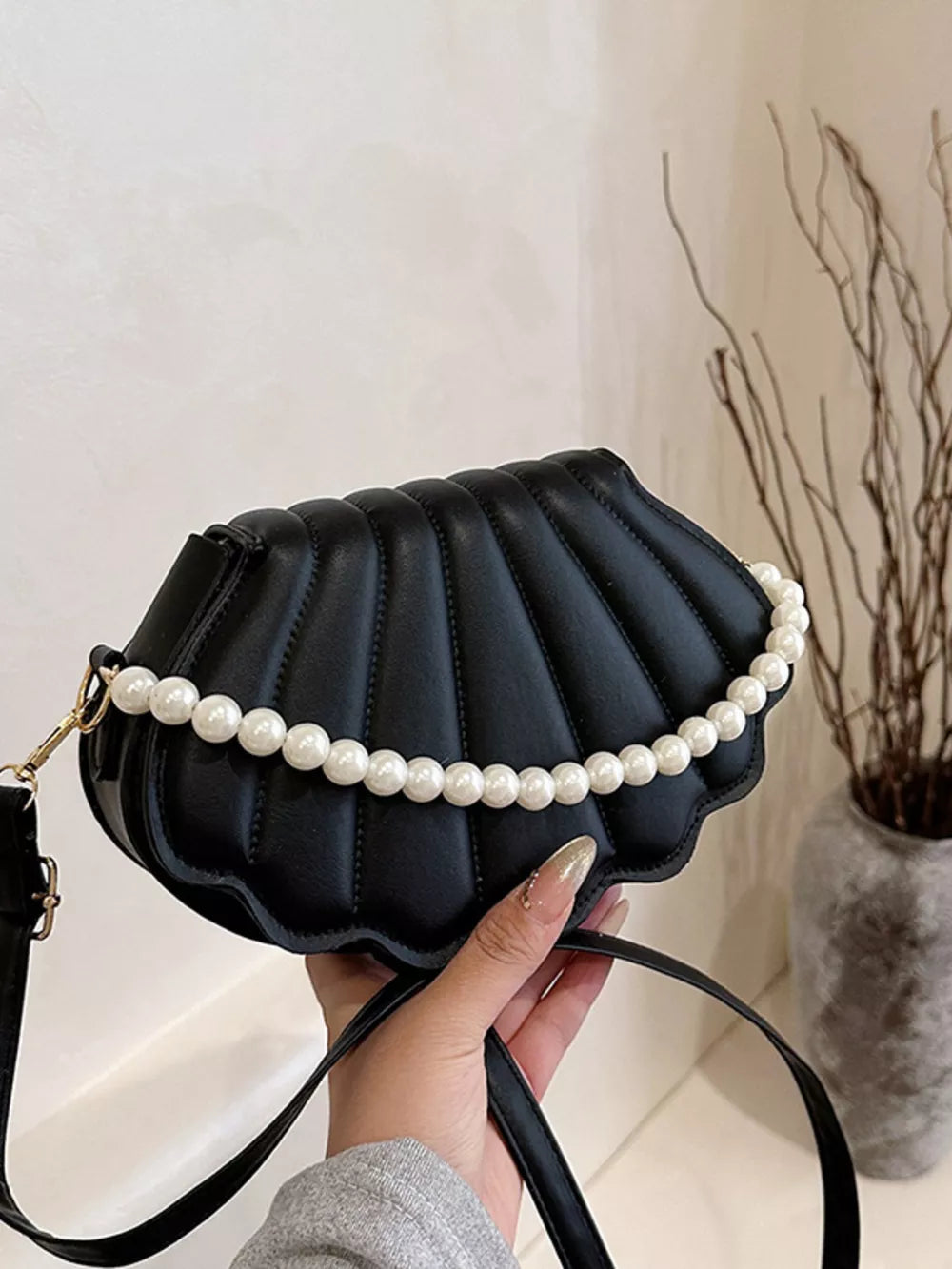 Black shell crossbody bag with pearl embellishment and quilted detail.