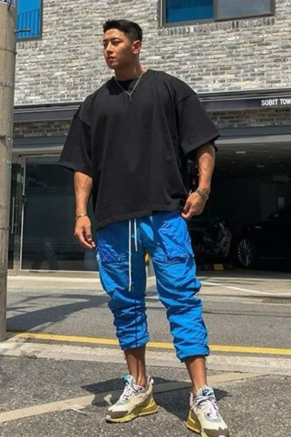 Black oversized drop-shoulder tee with a crew neck and short sleeves.
