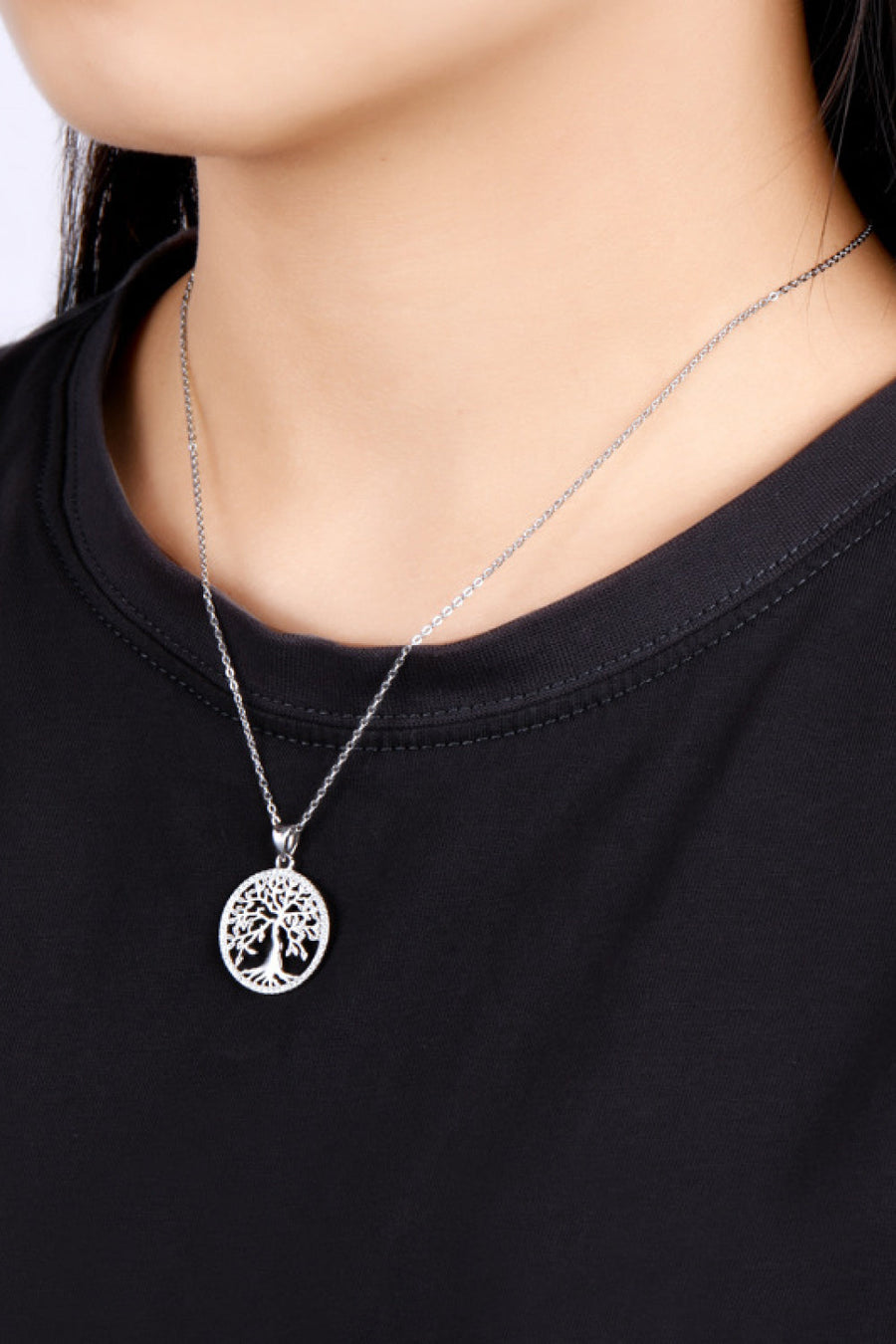Sterling silver Tree of Life necklace with a delicate chain on a black shirt.