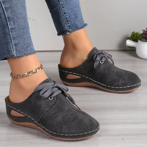 Dark gray perforated lace-up mule flats with white stitching and cut-out sides.