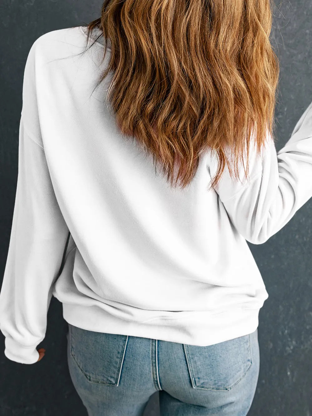 White crewneck sweatshirt with long sleeves, casual fit, paired with denim jeans.